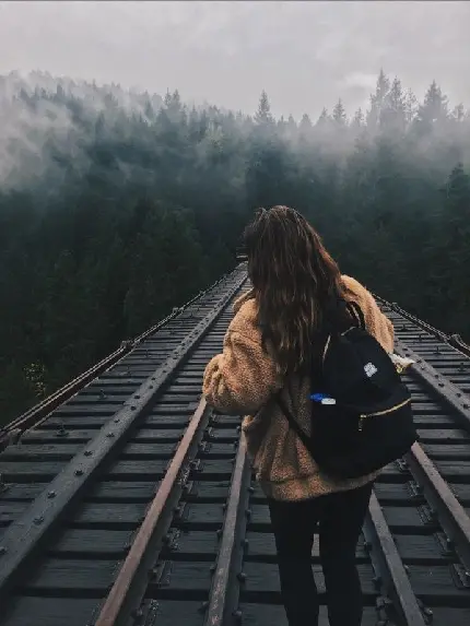 دانلود تصویر دختر در ریل قطار در وسط جنگل تاریک