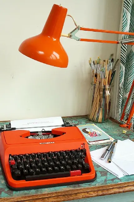 دانلود تصویر زمینه ماشین تحریر نارنجی بر روی میز مطالعه