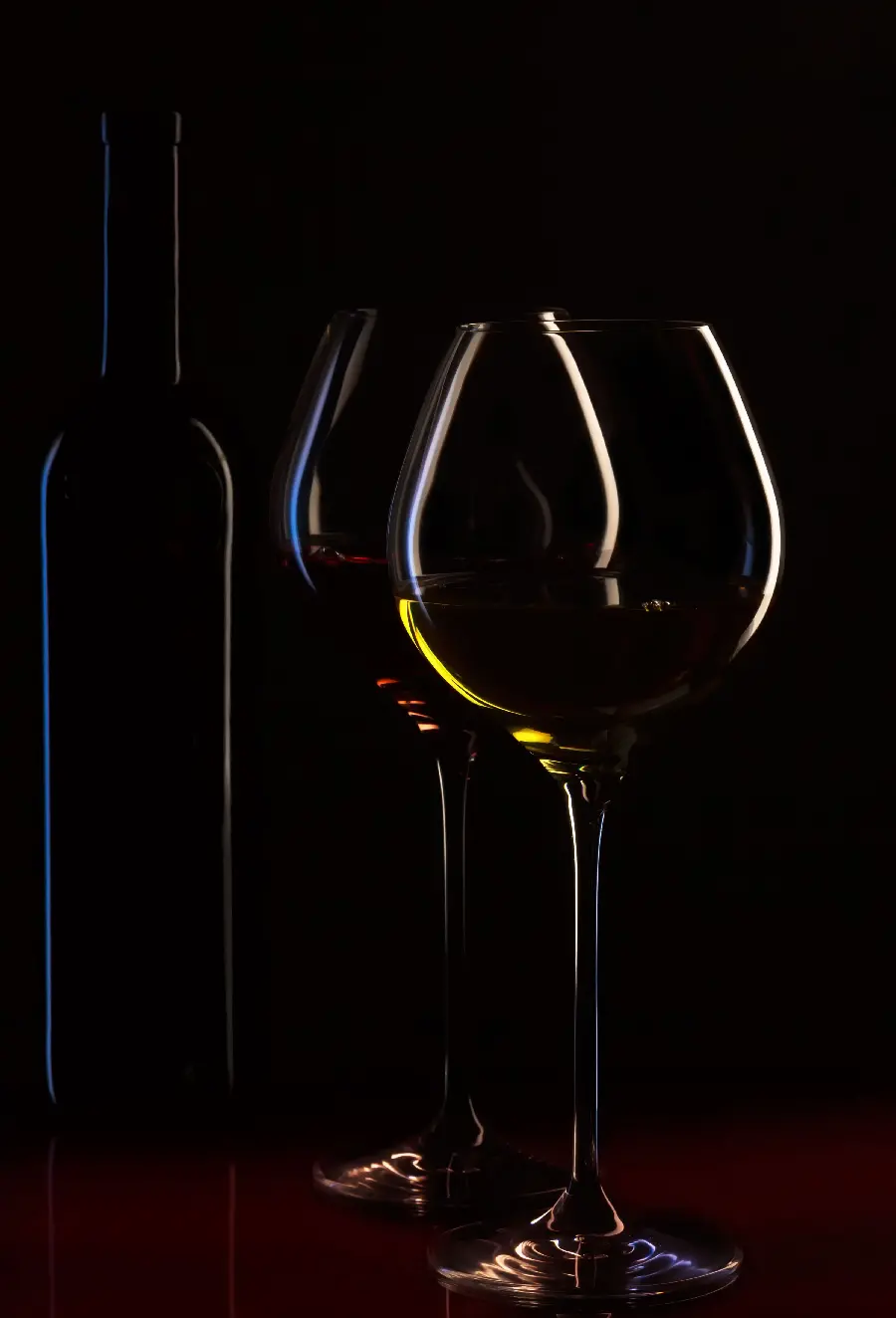 صحنه رمانتیک بطری نوشیدنی و لیوان در نور شمع