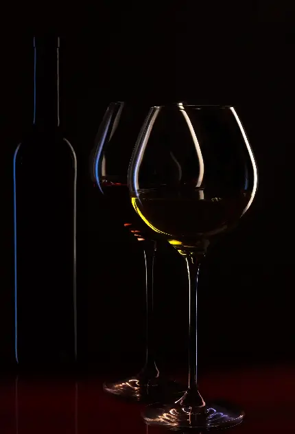 صحنه رمانتیک بطری نوشیدنی و لیوان در نور شمع