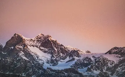 تصویر کوه های آلپ با برف و نور صورتی در غروب