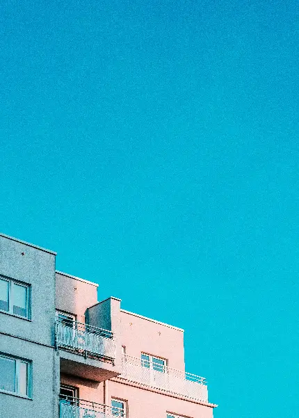تصویر ساختمان های آبی و صورتی در آسمان آبی پوزنان با کیفیت بالا
