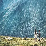 عکس دو کودک در حال ایستادن در چمن با منظره کوهستان
