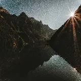 تصویر کوهستان و انعکاس آن در آب هنگام طلوع آفتاب با کیفیت 4K