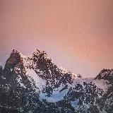 تصویر کوه های آلپ با برف و نور صورتی در غروب