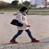 تصویر زن با شال و سوئیشرت در حال پیاده روی برای طراحی پاییزی