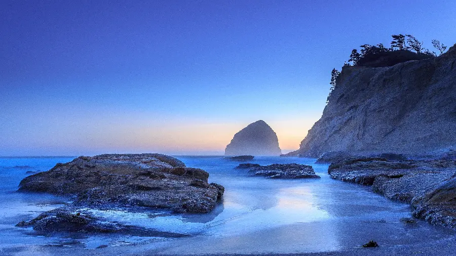 تصویر زمینه رویایی آبی رنگ از صخره های کوتاه و بلند در ساحل اقیانوس بسیار با کیفیت