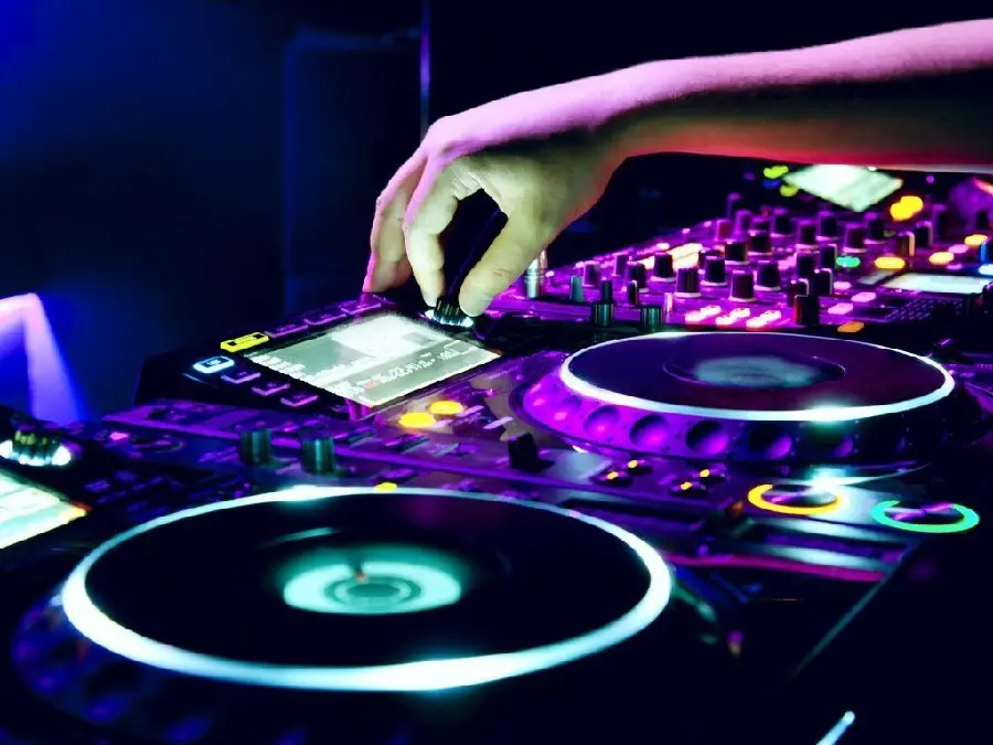 عکس با کیفیت دی جی dj در حال تنظیم و میکس آهنگ و نور بنفش