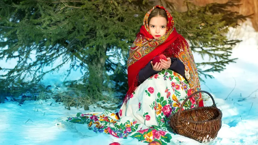 عکس استوک چشمگیر از دختر بچە کیوت و مهربان با سیبی قرمز در دستانش با سبدی در کنارش و درختی سبز