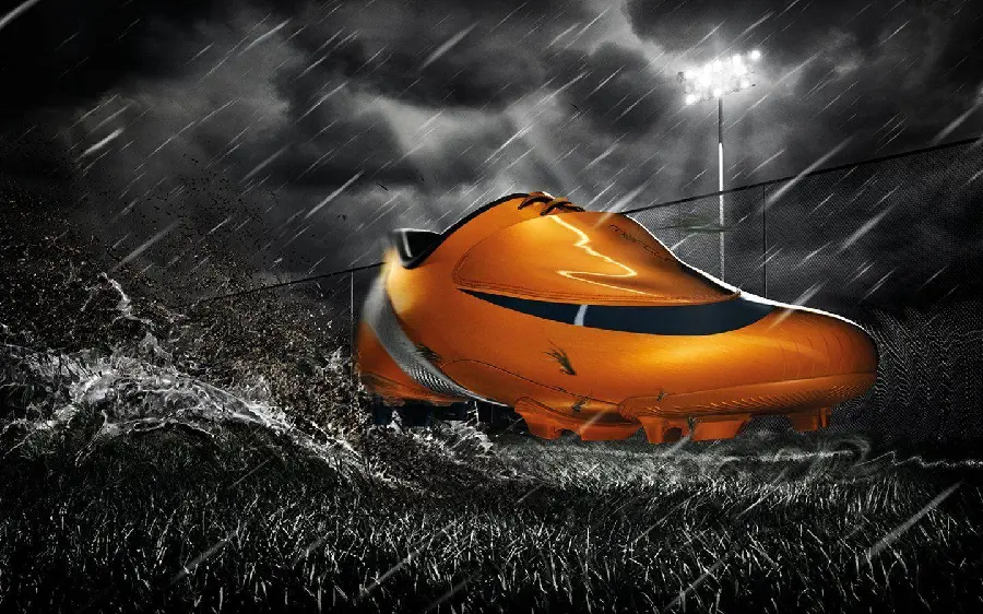 عکس شاهکار از کفش فوتبال نارنجی رنگ Nike با زمینه بارانی تاریک 