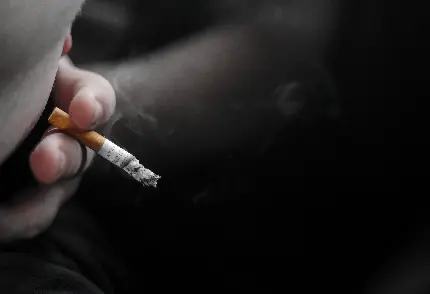 تصویر استوک مشخص از دستی نزدیک دهان در حالت دود کردن سیگار