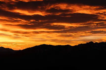 عکس استوک آسمان استثنایی با ابرهای نارنجی بر فراز کوه های استوار