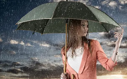 پس زمینە زیبا خاص لپ‌تاب از دختر شیک پوش لباس مرجانی رنگ با چتری در دست در باران واقعی باکیفیت hd