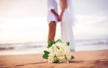 عکس زمینە کدر از عروس و داماد و دستە گلی در ساحل