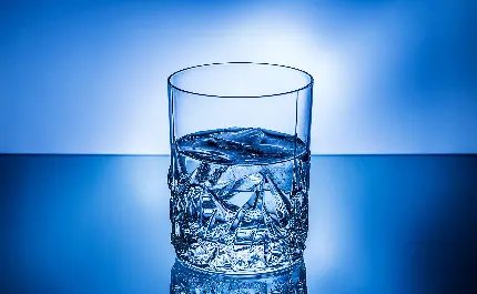 پس زمینه ی آبی لاجوردی از لیوان برجسته ی آب آشامیدنی با هاله ی سفید
