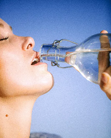 عکس زنی در حال نوشیدن آب زلال بطری شیشه‌ای باکیفیت ناب و مناسب تبلت
