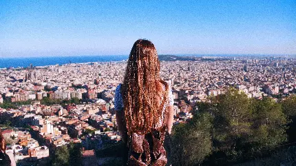 تصویر دختر مو قهوەای کیوت با کولە‌پشتی در حال نگاە کردن بە جاهای دیدنی شهر بارسلونا