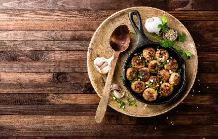 مهم ترین تصویر استوک از غذای متداول و خوشمزه ی کوفته ی برشته در ماهیتابه همراه سیر و یک شاخه جعفری روی میز چوبی