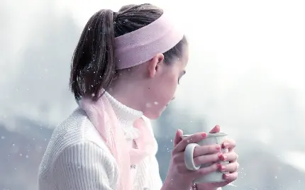 نمای هنری از دختر کیوت و زیبا در حال نوشیدن چای در هوای سرد 