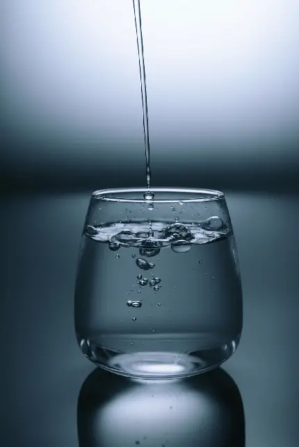 پوستری سیاه و سفید از لحظه ی جاری شدن آب آشامیدنی در لیوان کوچک