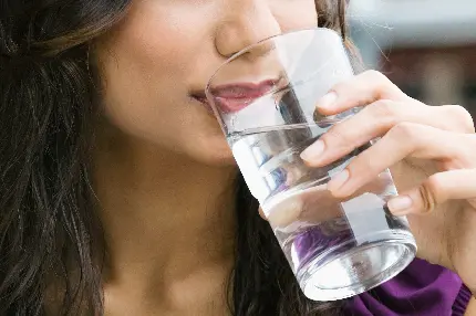 دانلود عکس استوک دختر زیبارو در حال نوشیدن آب آشامیدنی با لیوان