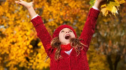 دختر بچه شاد با لباس قرمز رنگ در یک طبیعت پاییزی 
