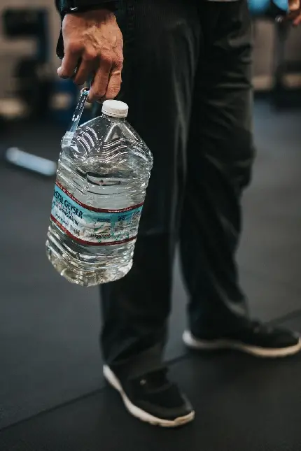 پوستری وسیع از بطری آب معدنی آشامیدنی در دست مردی