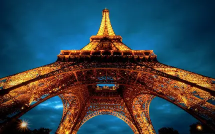 تصویر فانتزی نو و زوم شدە در شب از پایە‌های بنای تاریخی برج ایفل شهر پاریس نماد فرهنگ کشور فرانسە