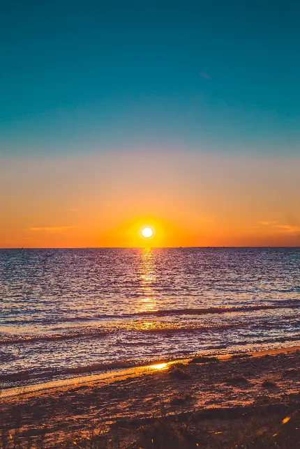 دانلود عکس غروب خورشید در پشت خط افق نارنجی رنگ دریا