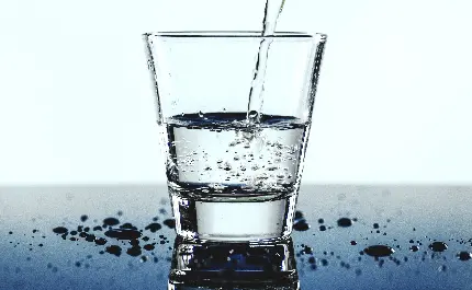 تصویر عجیب لیوان در حال پر شدن از آب آشامیدنی با قطرات آب در اطرافش 