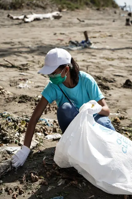 عکس دختر دوستدار محیط زیست در حال جمع آوری زباله های خاک