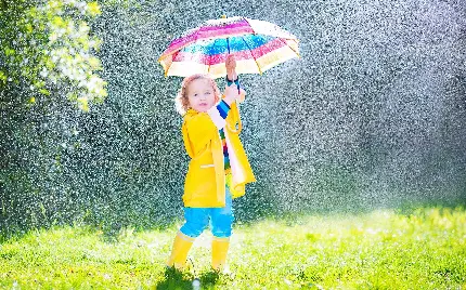 تصویر دختر بچه کیوت با چتر رنگی زیر باران فصل بهار