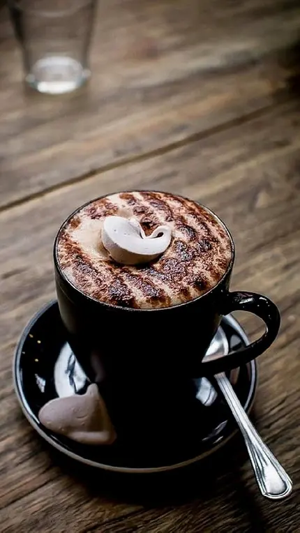 فنجان قهوه شیک با تزئین شگفت انگیز روی میز کافی شاپ