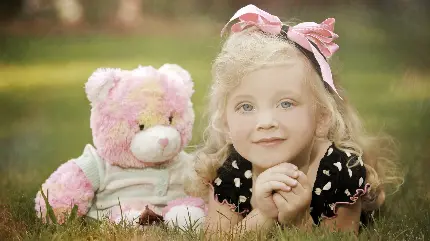 عکس دختر بچه با موهای بلوند در کنار عروسک خرس