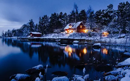 خانه ای برفی با چراغ روشن در حاشیه دریاچه اسکاندیناوی	