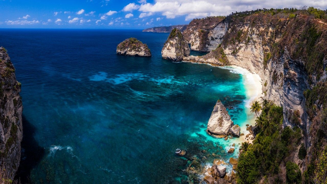عکس صخره های ساحلی جالب در کنار دریا آبی رنگ بالی
