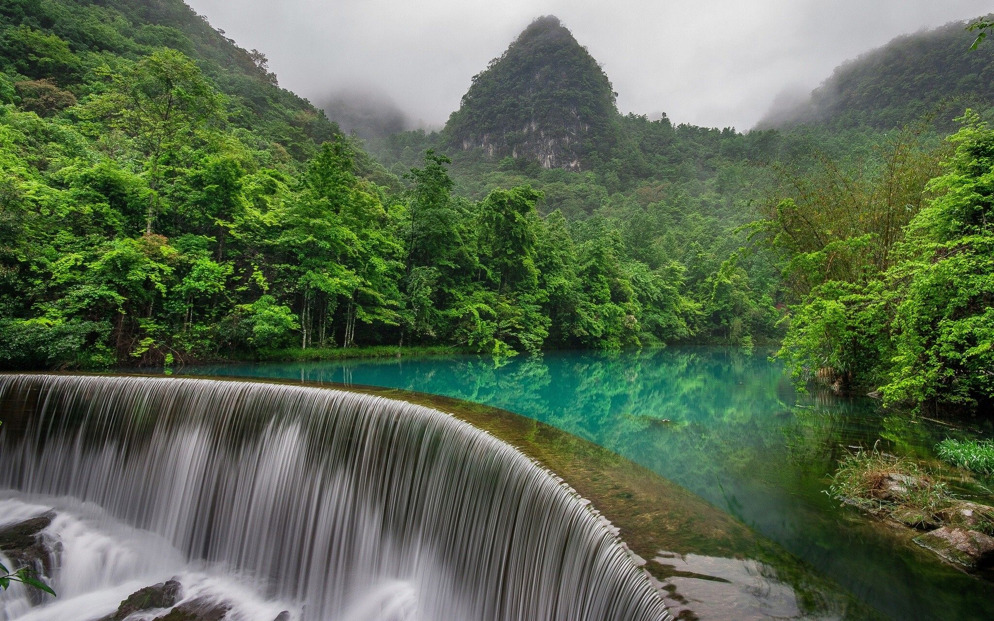 آبشار عظیم منتهی به رودخانه درون جنگل در یک قاب زیبا 