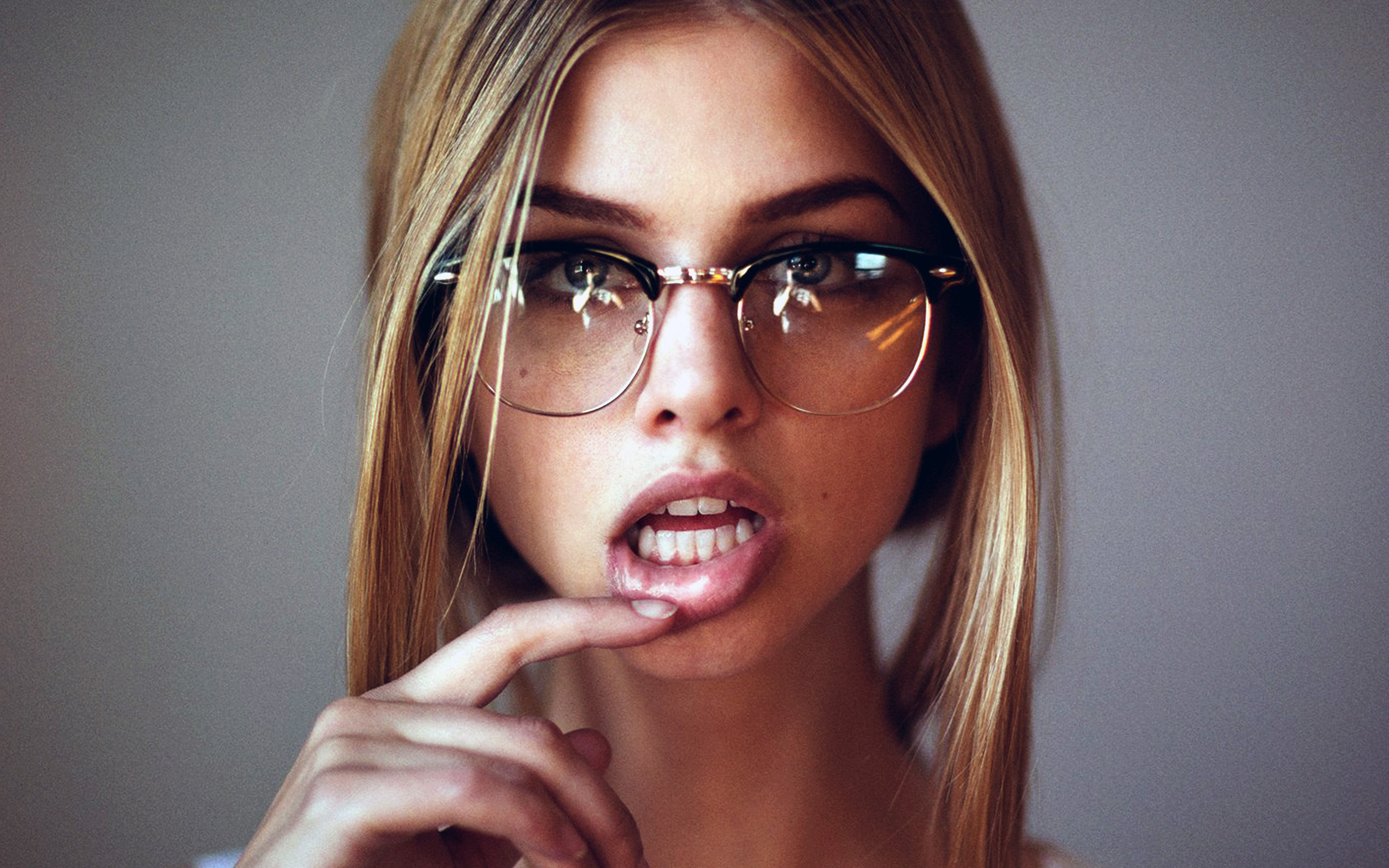 عکس دختر عینکی زیبا با موی طلایی با ژست انگشت به دهان فریبنده