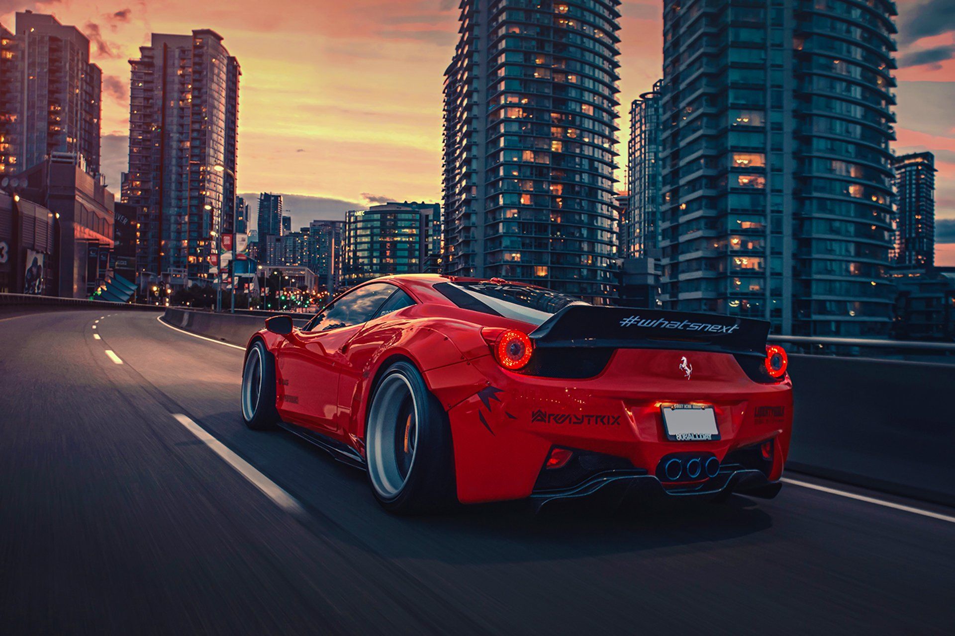 عکس جالب و دیدنی از ماشین قرمز در جاده با ساختمان های بلند کنار جاده 