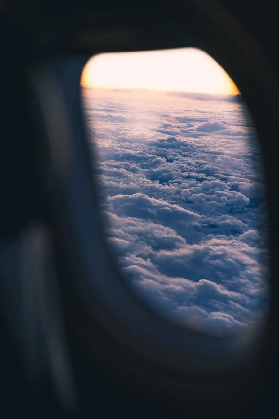 عکس پنجره کوچک هواپیمای مسافربری بر فراز ابرهای پنبه ای