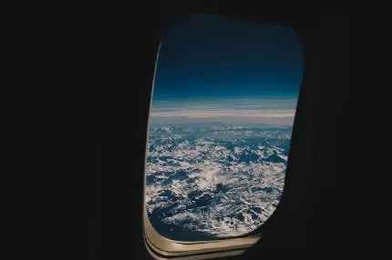 دانلود پس زمینه پنجره هواپیما بر فراز کوه های سفید پوش برفی