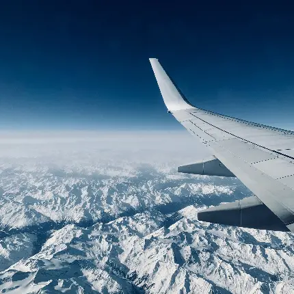 عکس بال هواپیما در حال پرواز بر فراز کوه های برفی زیبا