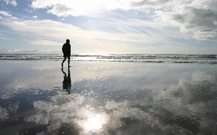 عکس زمینه پسر تنها غمگین در حال قدم زدن در ساحل دریا