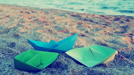 دانلود عکس پرکاربرد قایق های کاغذی رنگی کوچک روی شن های ساحل