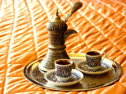 تصویر قهوه جوش سنتی در کنار فنجان های قهوه ترک با طرح آبی
