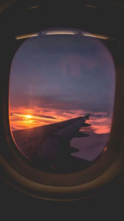 تصویر خاص پنجره هواپیما رو به منظره خورشید درحال غروب