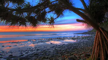 قاب HD تحسین برانگیز ساحل سنگی دریا زیر آسمان خوش رنگ غروب