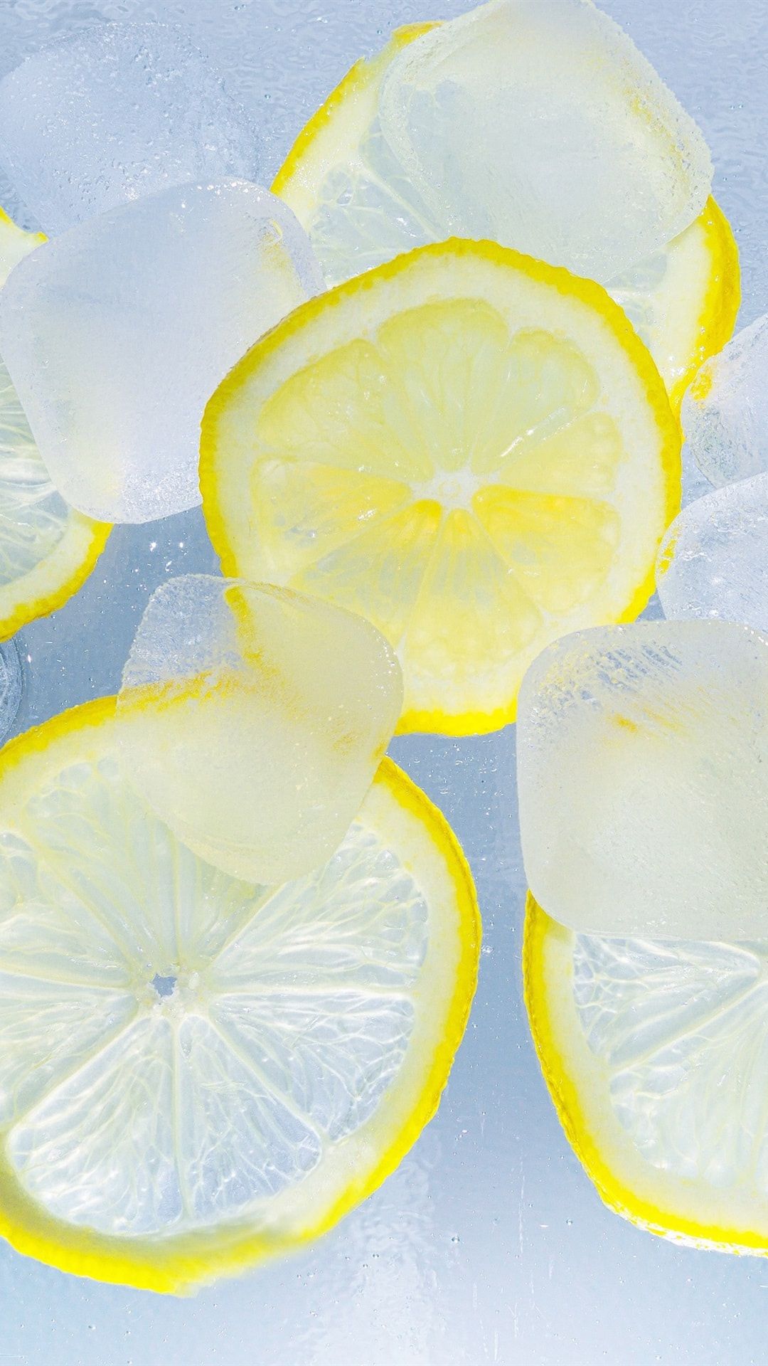 عکس استوک از لیمو های زرد رنگ ترش با یخ های مکعبی 