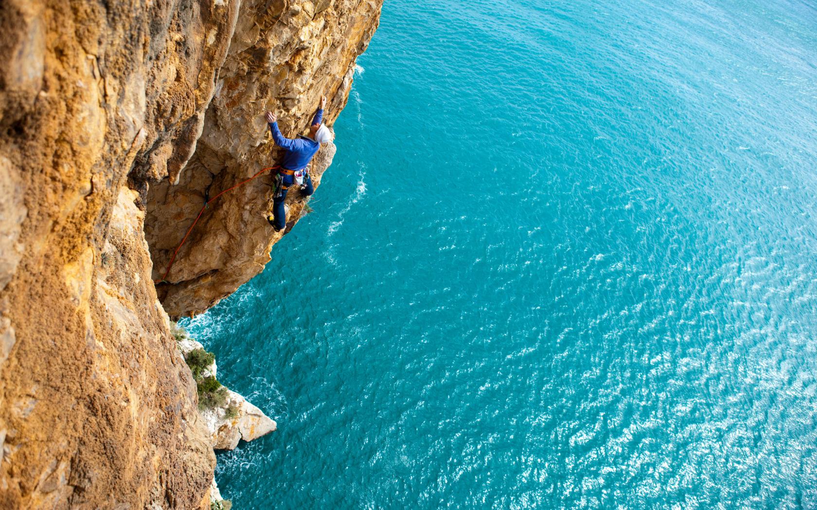 تصویر صخره نوردی شجاعانه بر فراز دریای آبی رویایی 