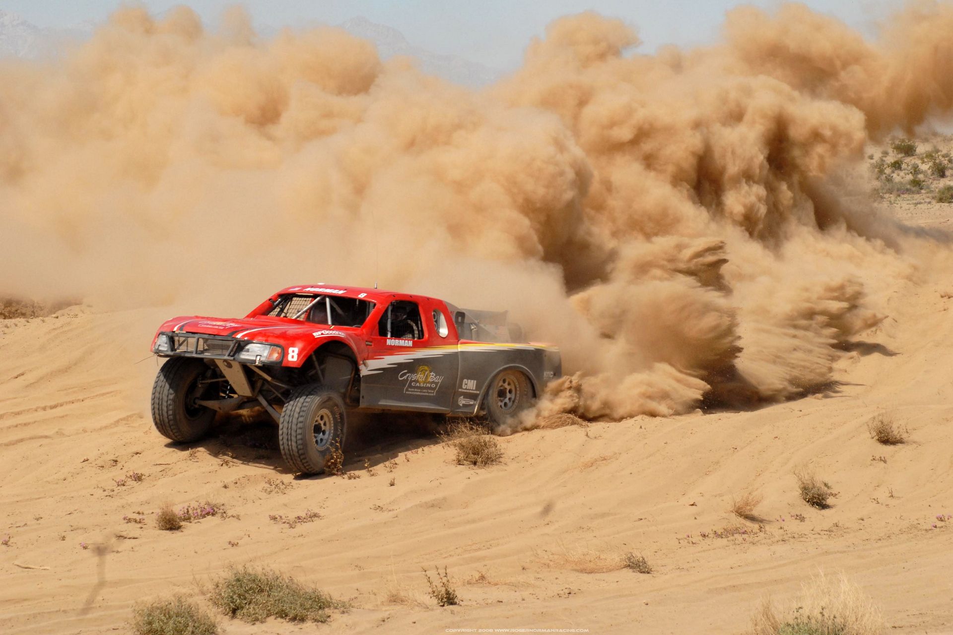 عکس خروش ماشین مسابقه قرمز و مشکی در شن ها در رالی داکار حیرت برانگیز